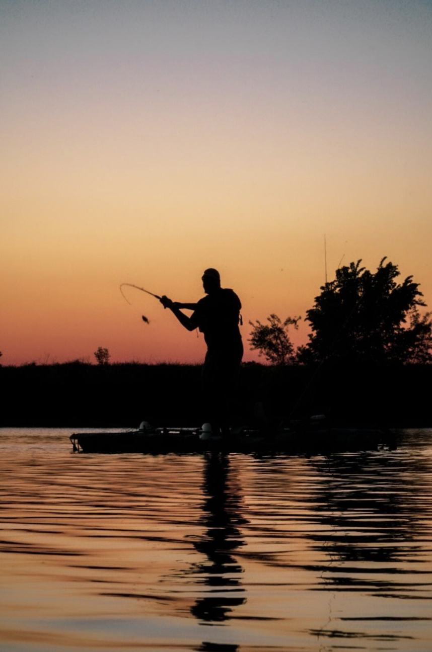Man fishing from kayak at sunset